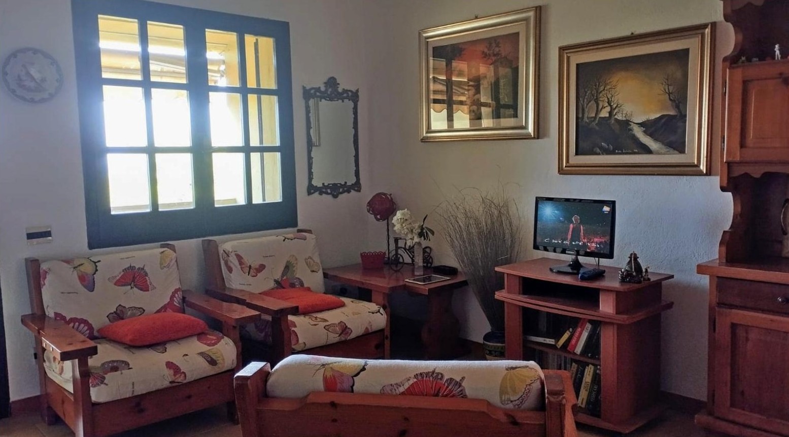 Sala con TV, poltrone e finestre sul mare