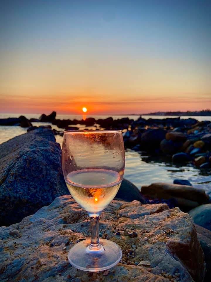 Calice di vino bianco al tramonto sugli scogli